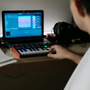 Home A music producer uses a synthesizer and laptop for composing in a home studio.