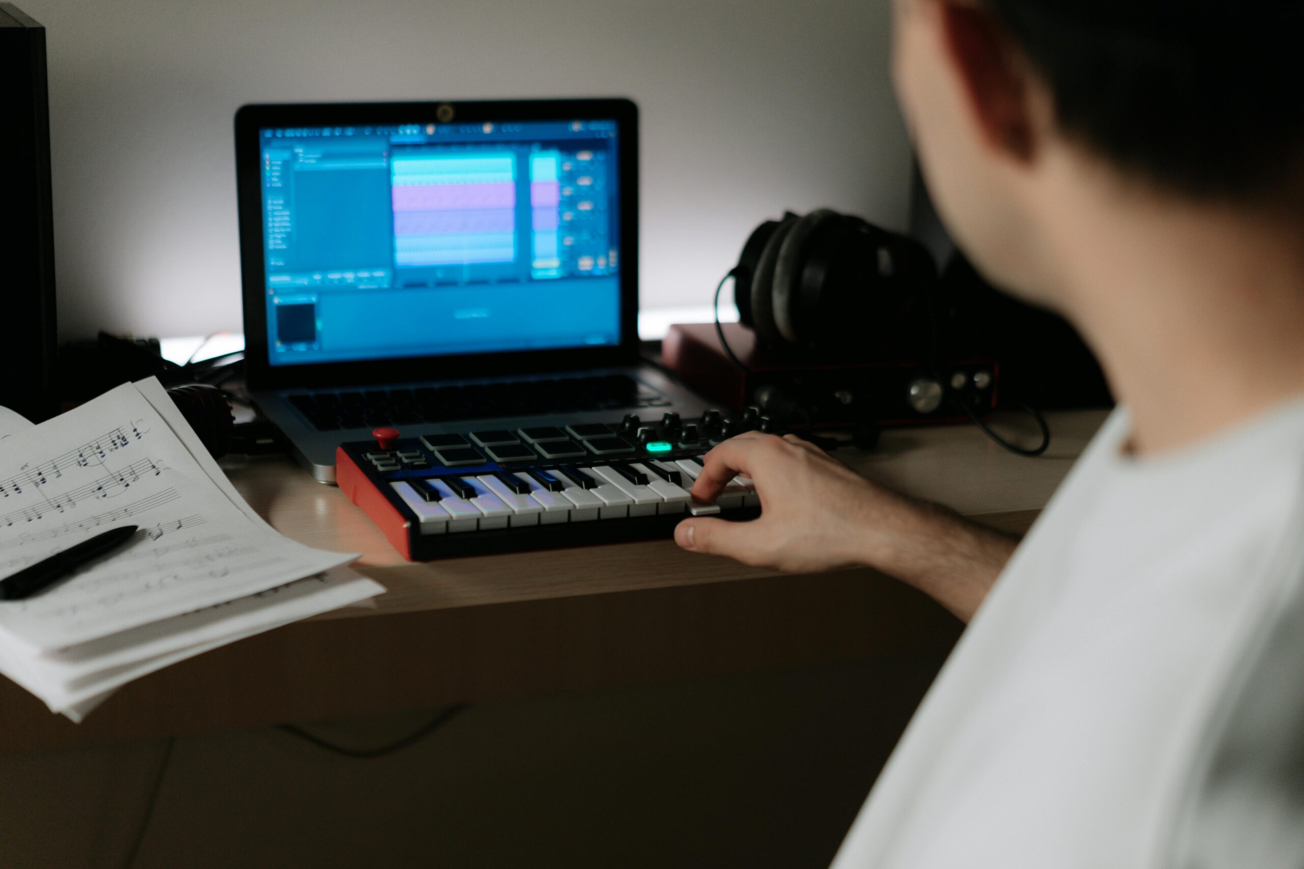 pexels photo 7096811 7096811 A music producer uses a synthesizer and laptop for composing in a home studio.